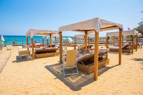 a beach with many beds and umbrellas on the sand at Pietrablu Resort & Spa - CDSHotels in Polignano a Mare