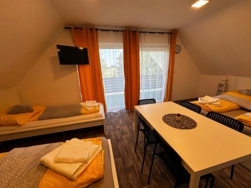 a room with two beds and a table with chairs at See Panzió in Fertőrákos
