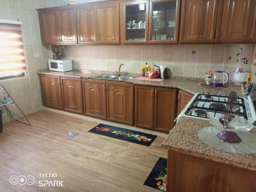 a kitchen with wooden cabinets and a counter top at بيت مزرعة ريفي in Madaba