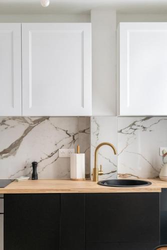 - une cuisine avec des murs en marbre blanc et un évier dans l'établissement Charming Parisian Flat near Eiffel Tower, à Paris