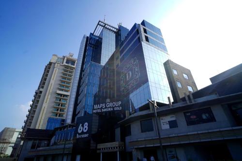a tall glass building with a sign on it at Hotel Sakura Gold in Gurgaon