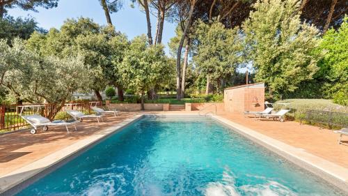 a swimming pool with chairs and trees in the background at ANTICO CERASO 10, Emma Villas in Grottaferrata