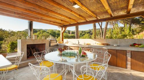 a patio with a table and chairs and a fireplace at ANTICO CERASO 10, Emma Villas in Grottaferrata