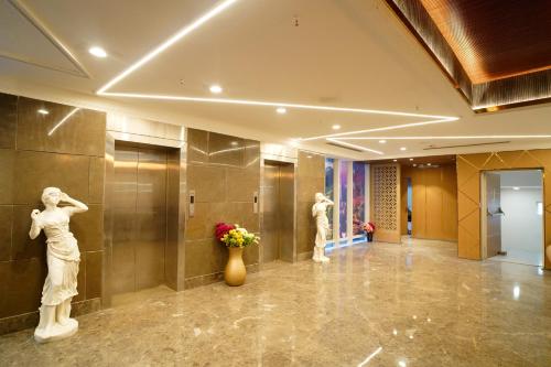 two statues of women in a lobby with flowers at Hotel Sakura Gold in Gurgaon