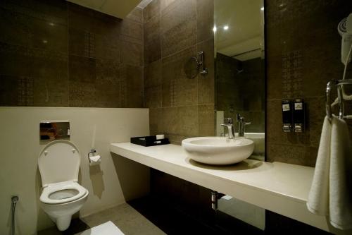 a bathroom with a sink and a toilet and a mirror at Hotel Sakura Gold in Gurgaon