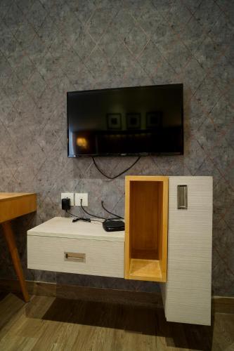 a flat screen tv on a wall with a cabinet at Hotel Sakura Gold in Gurgaon