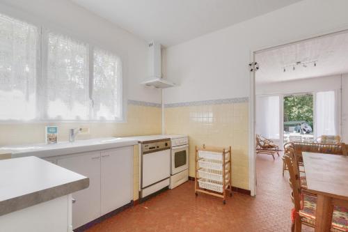 - une cuisine avec des appareils blancs, une table et des chaises dans l'établissement À moins de 2km de la plage, maison pour 6, à Andernos-les-Bains