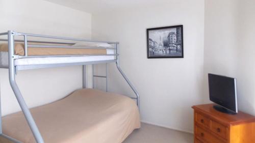 a bedroom with two bunk beds and a television at Breakwater Views Apartment 2 Cabarita Beach in Cabarita Beach