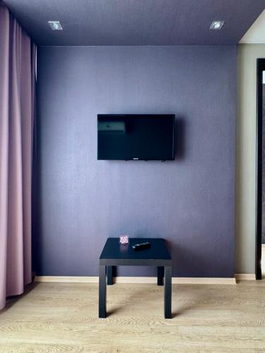 a living room with a table and a tv on a wall at Гоголя 68 in Karagandy