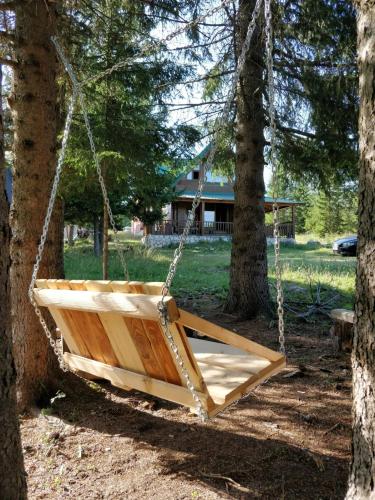 a wooden swing hanging between two trees at Vikendica Bianka u selu Uskoci in Žabljak