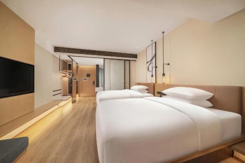 a bedroom with two large white beds and a flat screen tv at Fairfield by Marriott Shenzhen Dameisha in Shenzhen