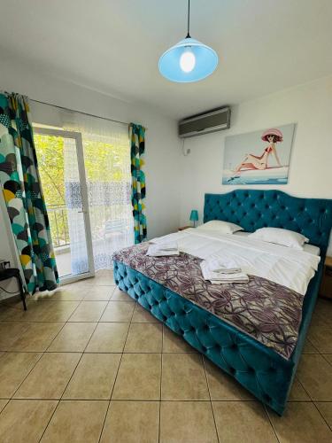 a bedroom with a bed with a blue head board at Vila Timona in Eforie Nord