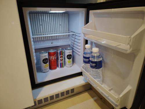 an open refrigerator with bottles of soda and water at The Straits Hotel & Suites in Melaka