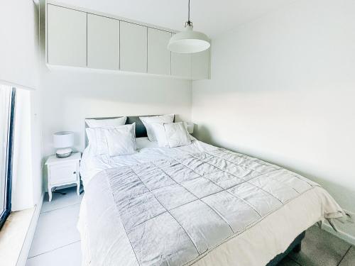 オーステンデにあるModern appartement centrum Oostende met enorm dakterras (parking beschikbaar)の白いシーツが敷かれた大きなベッドのある白い寝室
