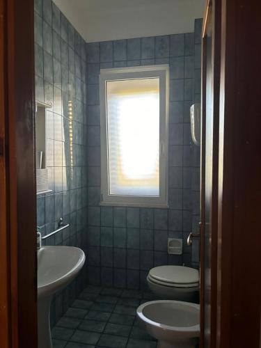 a bathroom with a toilet and a sink and a window at La casa di bruna in San Cataldo