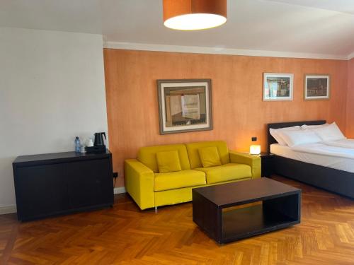 a hotel room with a bed and a yellow couch at Aquazzurra Resort & Aparthotel in Cannobio