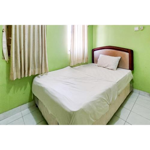 a bed in a room with a green wall at Surya Inn Syariah Cikarang RedPartner in Bekasi
