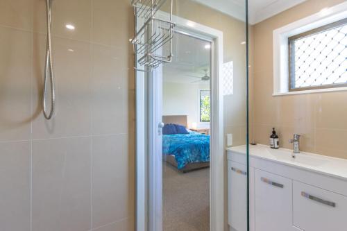 a bathroom with a shower and a sink and a bed at Shoreline Holiday Apartment in Hastings Point