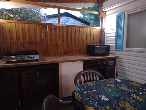 - une cuisine avec un bureau, un four micro-ondes et une table dans l'établissement Mobil Home climatisé avec terrasse dans camping l'Escale, calme à 900m de la plage, à Agde