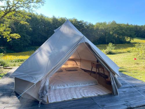 une tente grise avec un lit dans un champ dans l'établissement La tente Chemin d'étoiles, à Soturac