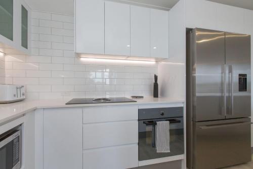 a kitchen with white cabinets and a stainless steel refrigerator at Dreamtime Villa in Kingscliff