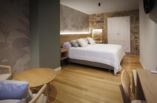a bedroom with a bed and a table and chairs at Casa da Praza in Lobios