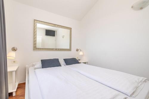 a white bedroom with a white bed and a mirror at Villa Haya with heated pool in Linardići
