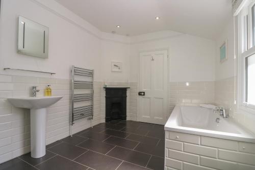 un bagno bianco con lavandino e vasca di 21 Passage Street formerly Panacea a Fowey