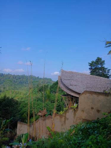 a building with a roof on top of a hill at Danaswari Bali Bamboo House in Selat