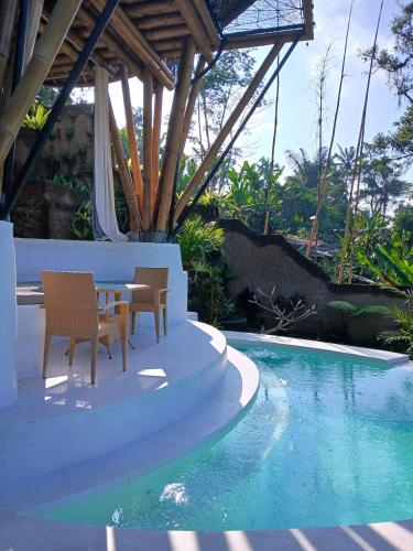 a patio with a table and chairs next to a swimming pool at Danaswari Bali Bamboo House in Selat