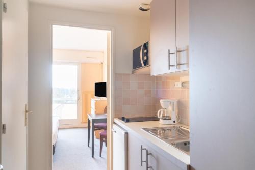a kitchen with white cabinets and a table in a room at Brit Hotel Le Parc Vichy in Bellerive-sur-Allier