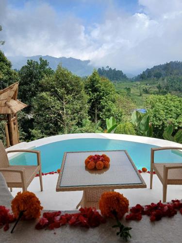 a table with a bowl of fruit on it on a patio at Danaswari Bali Bamboo House in Selat