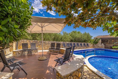 a patio with chairs and an umbrella next to a swimming pool at Villa Haya with heated pool in Linardići