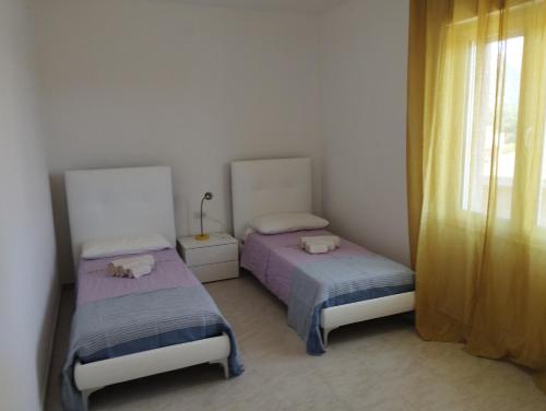 a bedroom with two beds and a window at Appartamento Sankt Johann in San Giovanni Suèrgiu