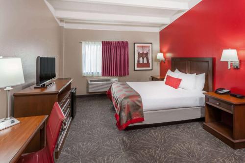 a hotel room with a bed and a television at Ramada by Wyndham Hammond Hotel & Conference Center in Hammond