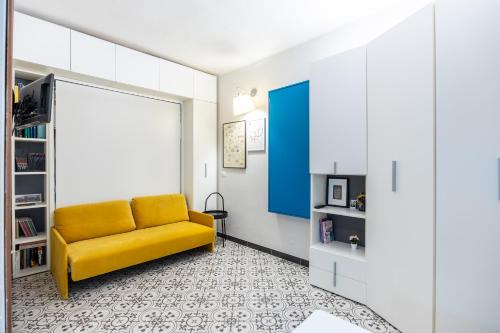 - un salon avec un canapé jaune et une porte bleue dans l'établissement Two Steps From-Duomo Design One Room Flat, à Milan