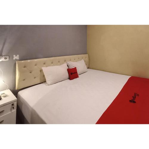 a bedroom with a bed with a red book on it at RedDoorz at Deluxe Hotel near Terminal Purabaya Bungurasih in Sidoarjo
