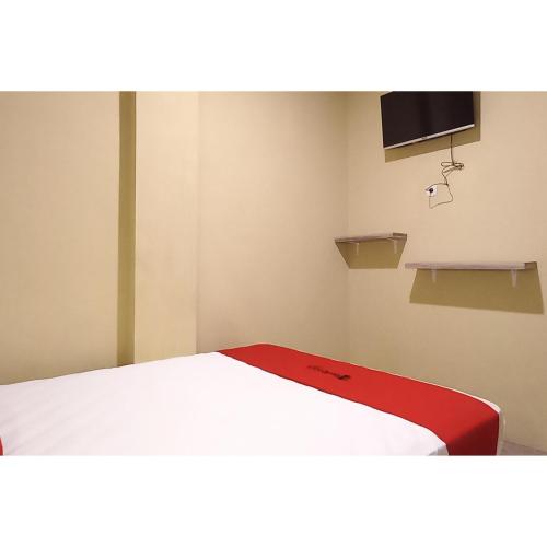 a room with a bed and a tv on the wall at RedDoorz at Deluxe Hotel near Terminal Purabaya Bungurasih in Sidoarjo
