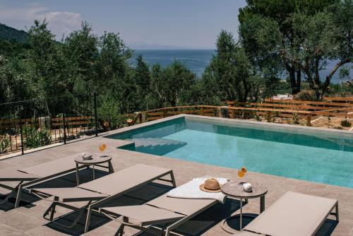 a swimming pool with two lounge chairs and a table and a pool at Villa Cossoro Ena in Zakynthos in Xirokástellon