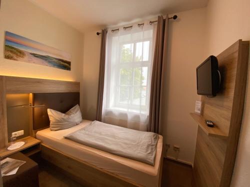 a small room with a bed and a window at Pension Zum Alten Fährhaus in Rostock
