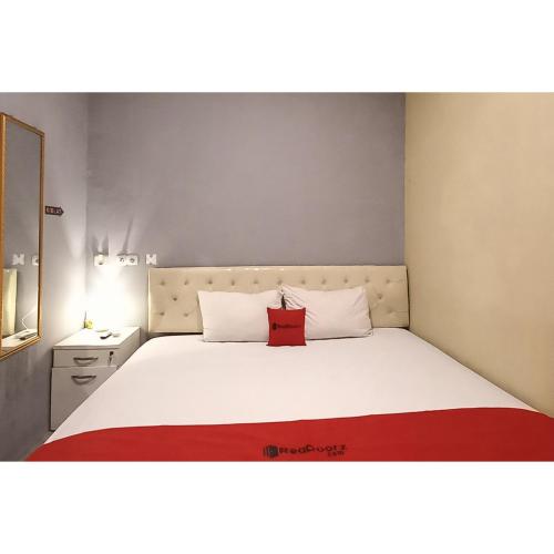 a bedroom with a large white bed with a red pillow at RedDoorz at Deluxe Hotel near Terminal Purabaya Bungurasih in Sidoarjo