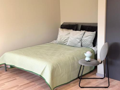 1 dormitorio con 1 cama con colcha verde y mesa en Green studio Valmiera, en Valmiera