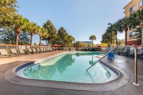 a swimming pool in a resort with chairs and trees at City Express by Marriott Orlando International Drive in Orlando