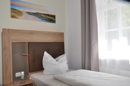 a bed with white pillows and a window in a room at Pension Zum Alten Fährhaus in Rostock
