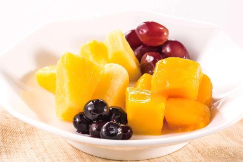 a bowl of fruit with oranges and grapes on a table at Comfort Hotel Himeji in Himeji