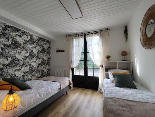 a bedroom with two beds and a window at LES "AGATHINES" Maison 4 chambres, de 1 à 9 personnes, deux logements indépendants in Ronce-les-Bains
