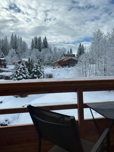 a balcony with a chair and snow covered trees at Hôtel Le Jeu de Paume in Chamonix-Mont-Blanc
