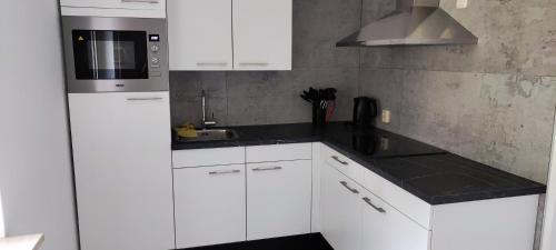 Una cocina blanca con fregadero y microondas. en Sparrenburg Oisterwijk, 4 persoons Bungalow, en Oisterwijk