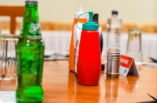 a wooden table with a bottle ofetchup and a soda bottle at Dovenest Lodge in Naivasha
