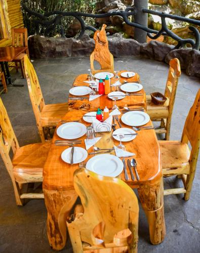 a wooden table with plates and utensils on it at Dovenest Lodge in Naivasha